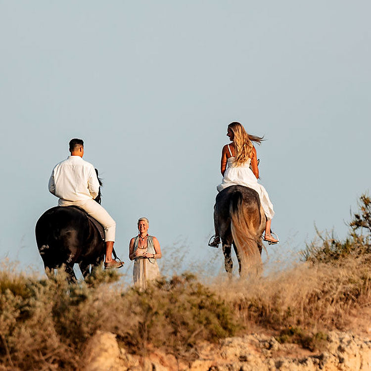 Brautpaar reitet auf Pferden zur freien Trauung an der Algarve, Traurednerin wartet am Strand